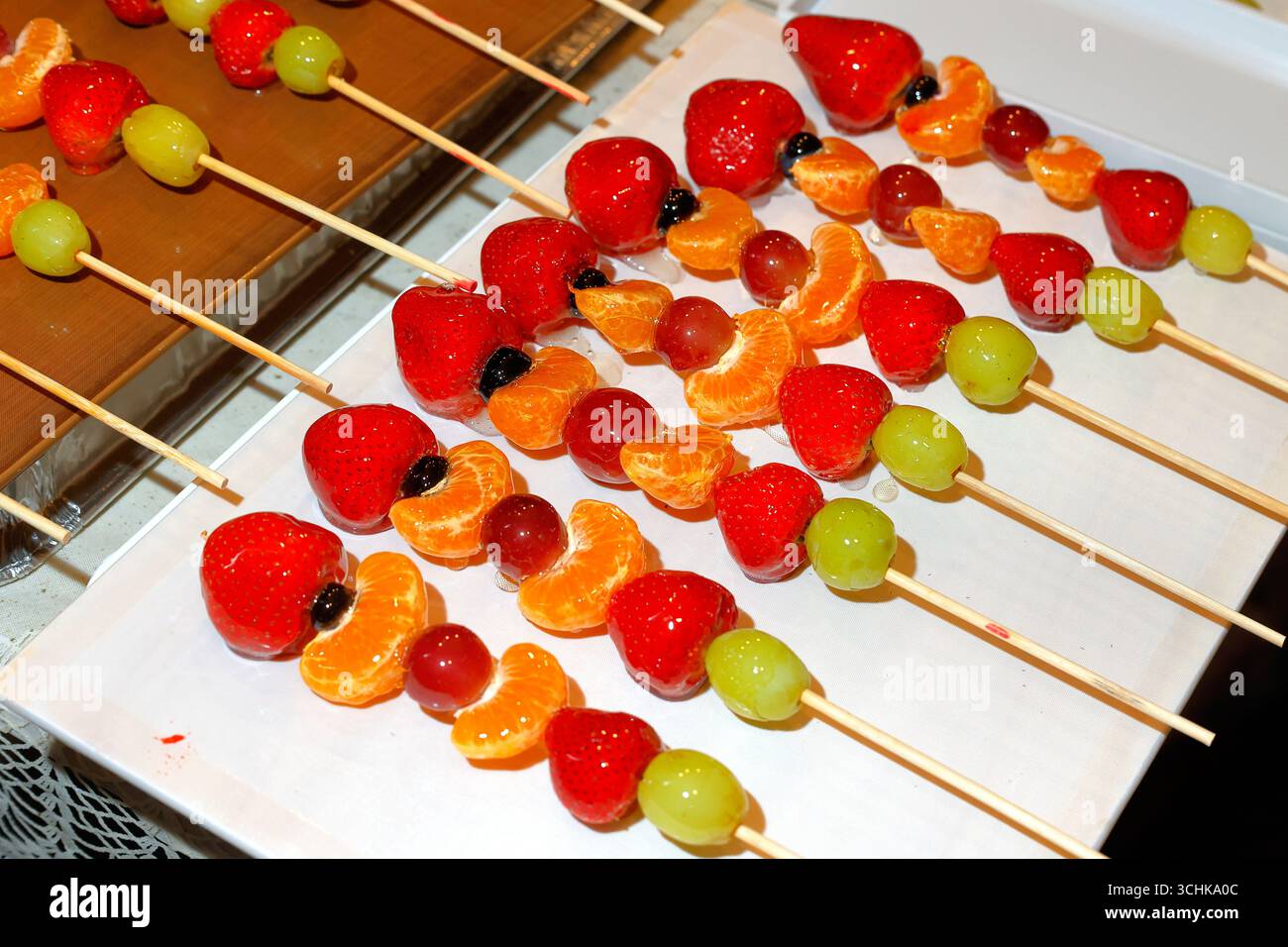 Tanghulu, candied skewered fruit, on a plate. Stock Photo