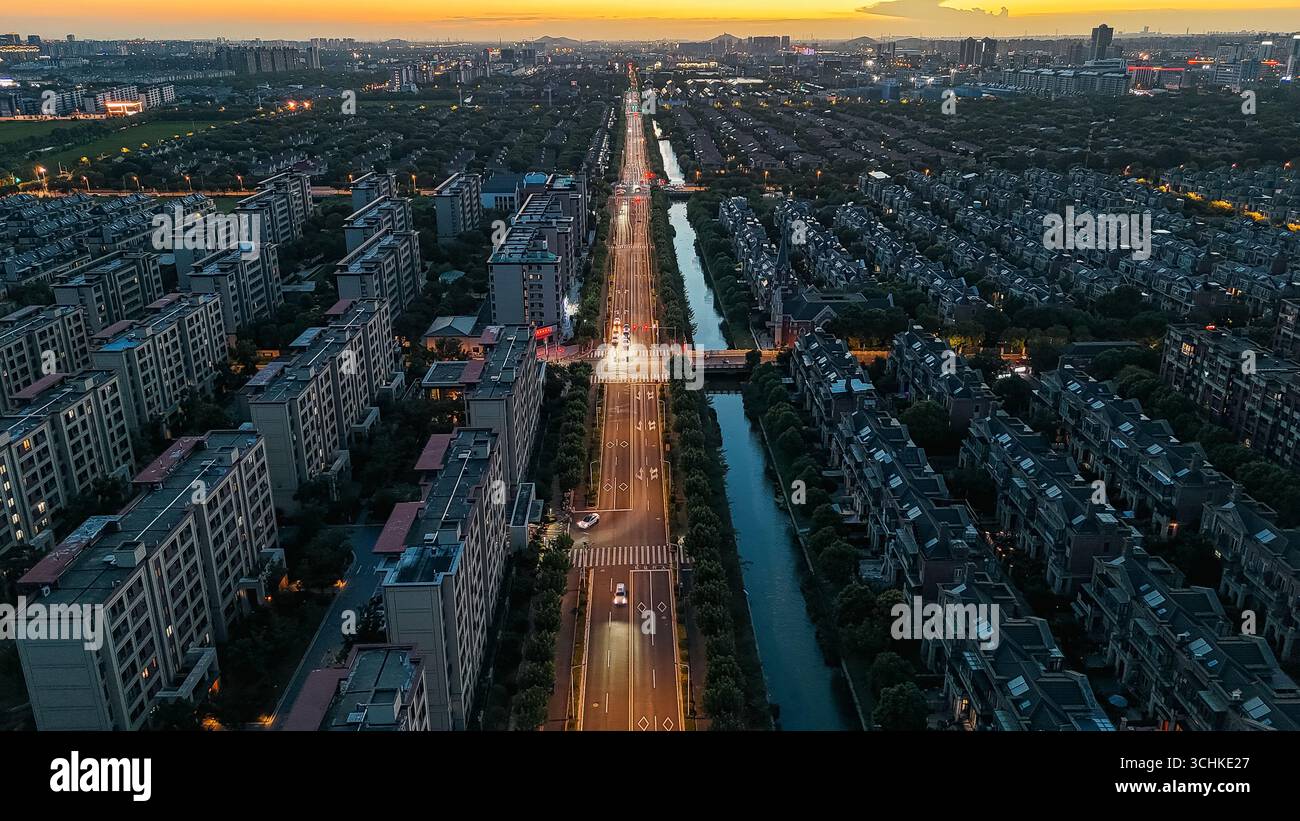 Aerial drone view of a modern city at sunset, showing a straight road ...