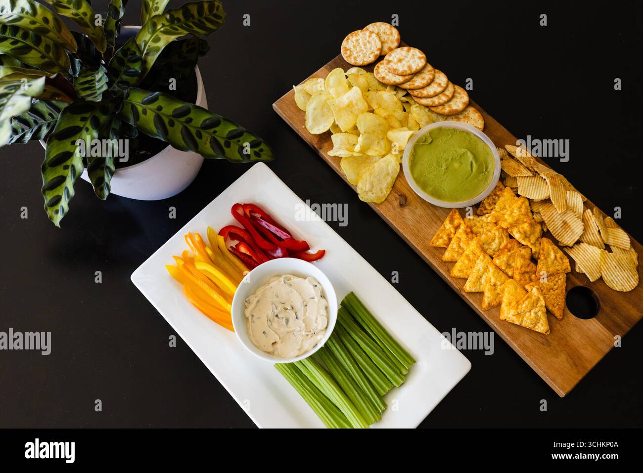 Colorful vegetable platter and chips with dips on table for party celebration, at home Stock Photo