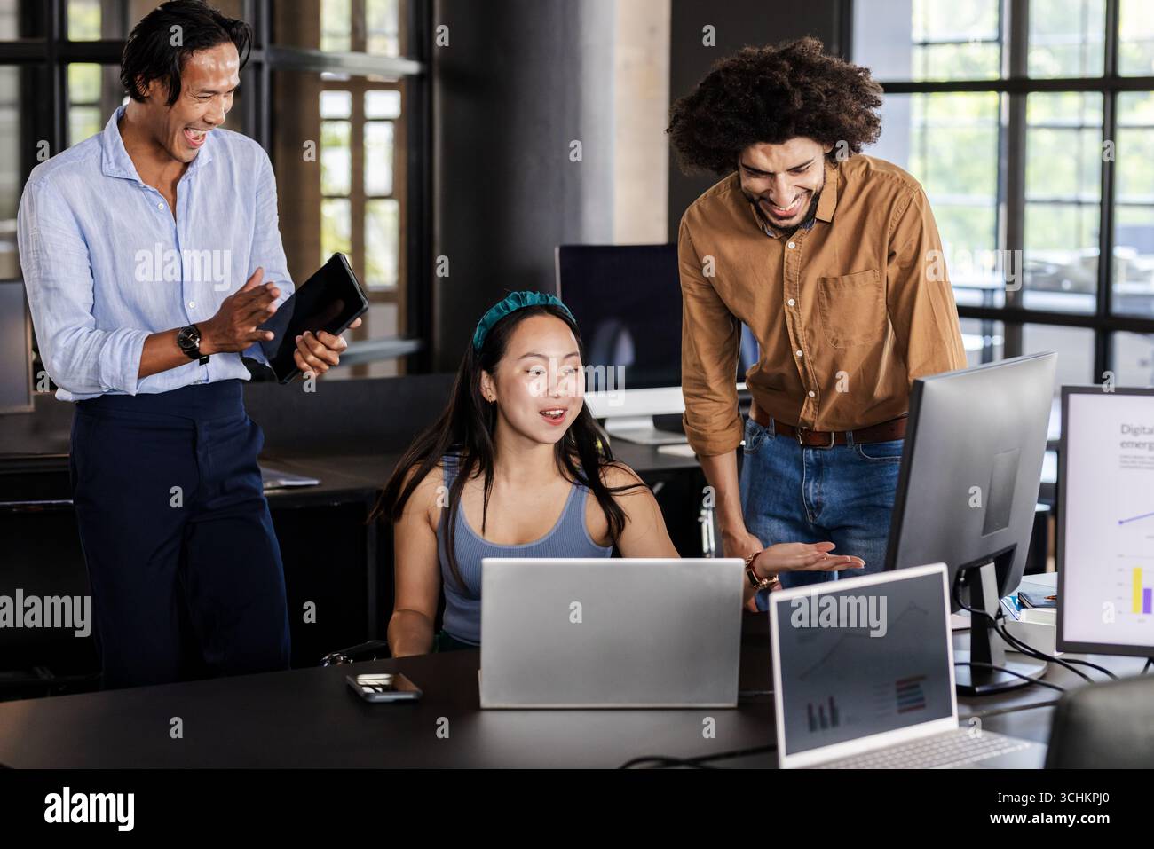 Diverse business team collaborating on project with laptops and digital charts, at office Stock Photo