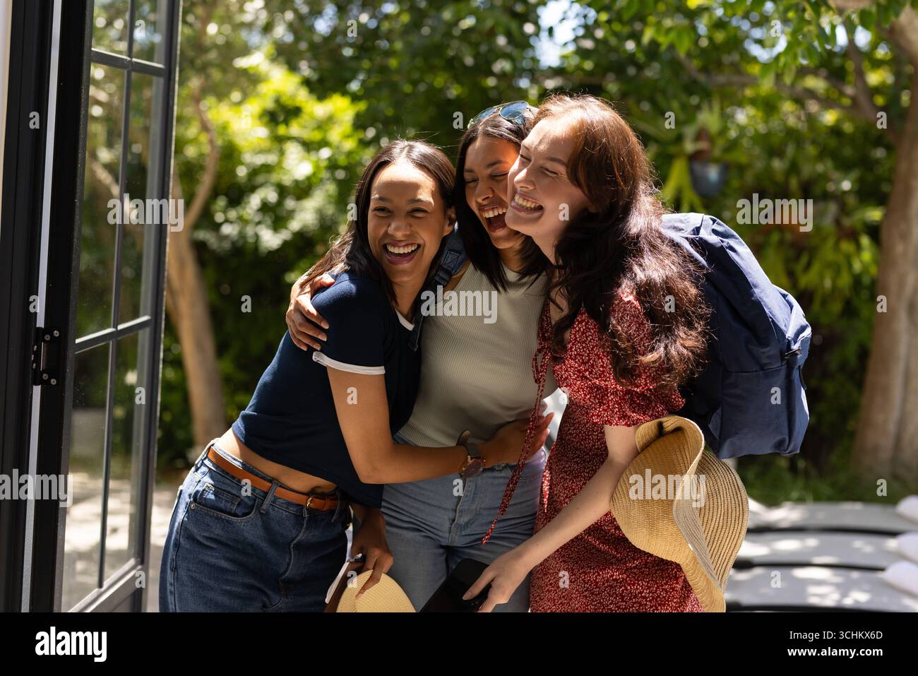 Laughing and embracing, three young women enjoy sunny day outdoors ...