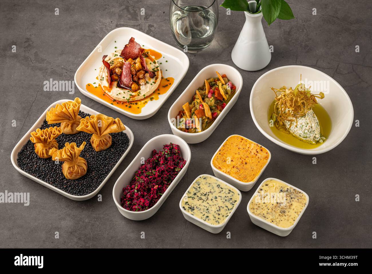 Assorted appetizers with dips, spreads, and vegetables on table Stock Photo