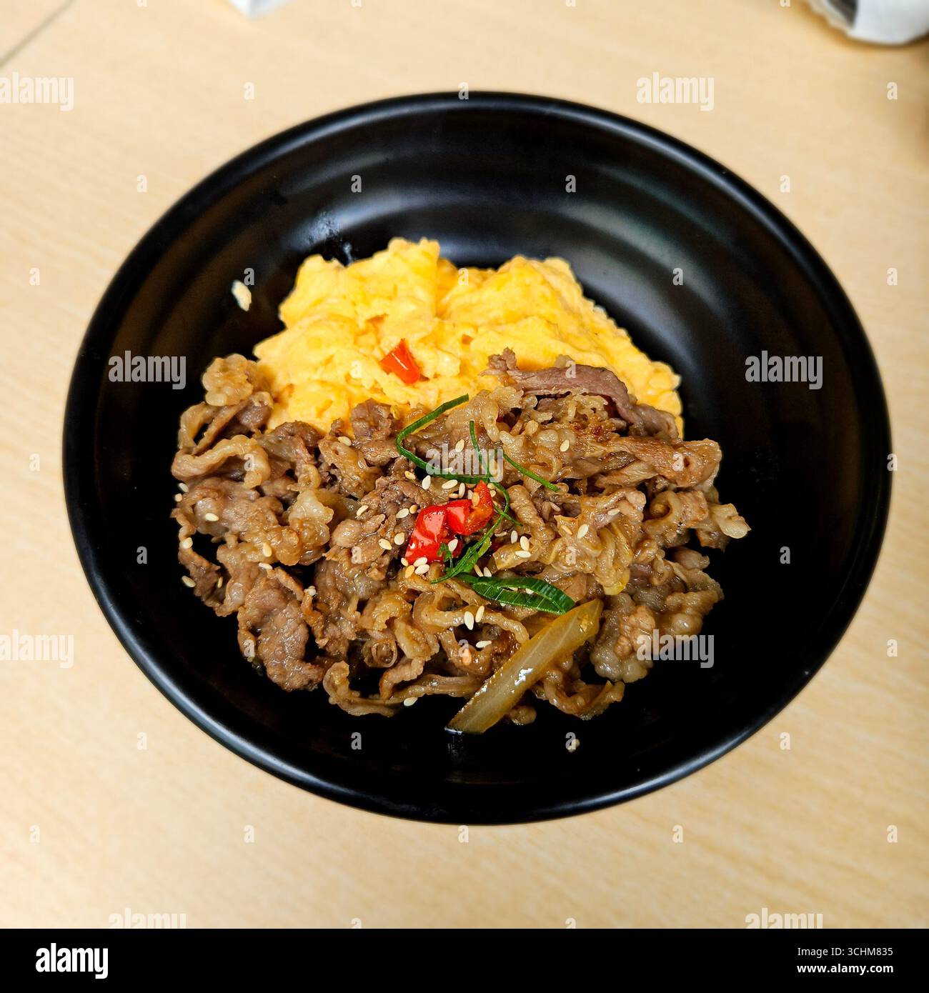 Delicious stir fried beef with scrambled egg served on rice in black bowl, Asian comfort food with savory taste - Smartphone Captured Stock Image