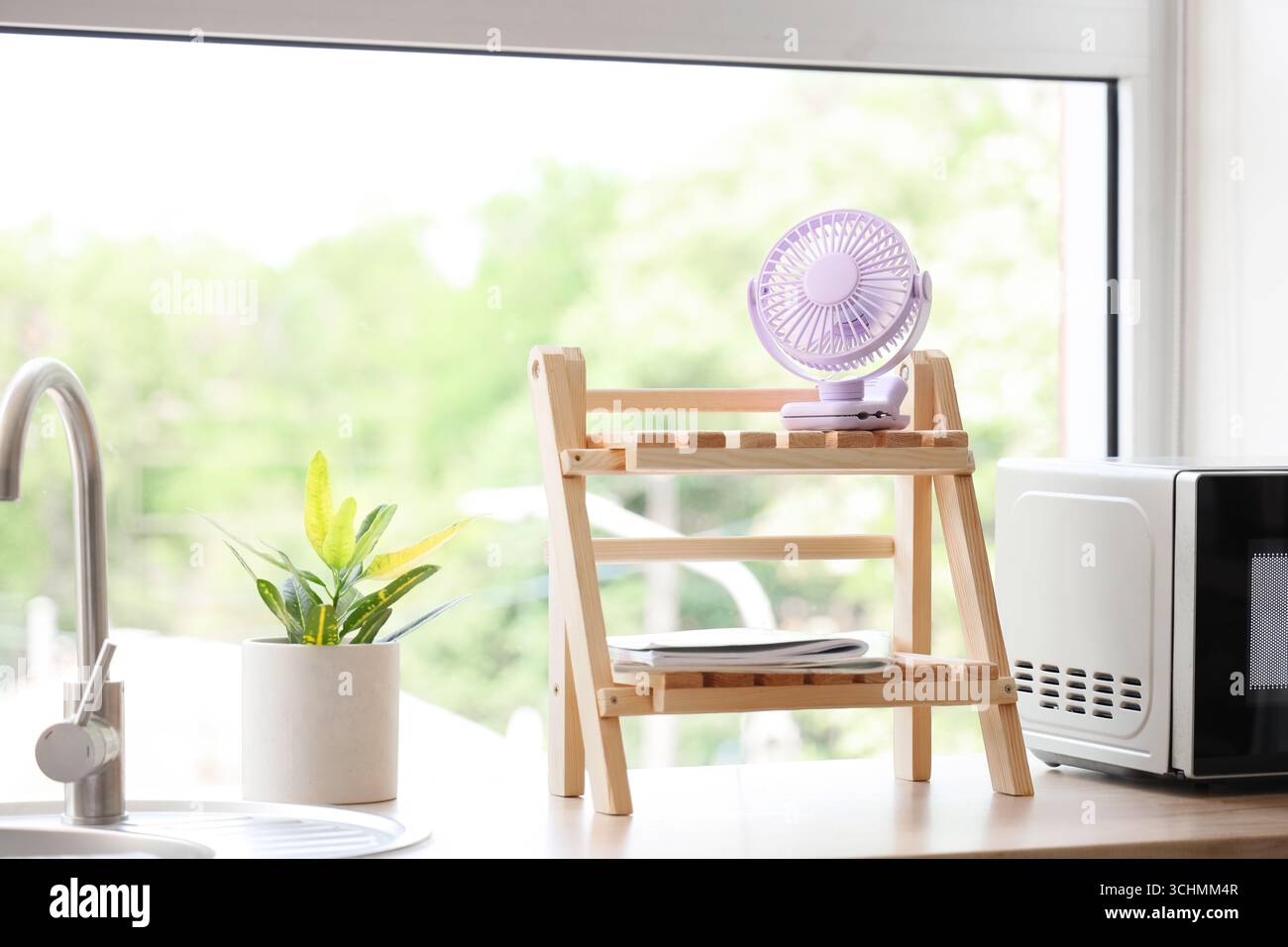 Lilac mini fan on shelf in kitchen Stock Photo