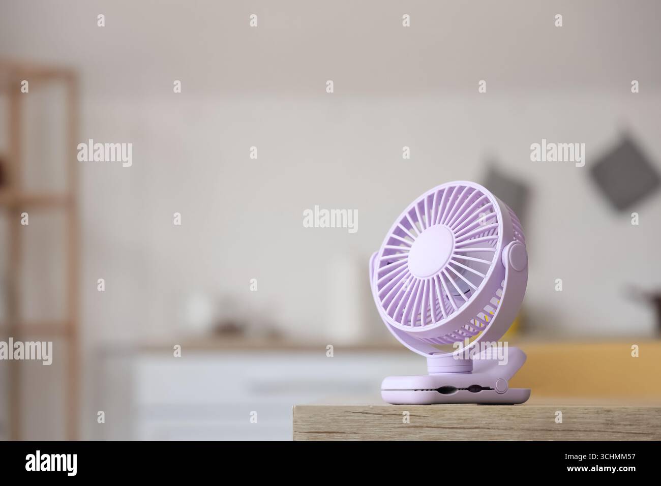 Lilac mini fan on table in kitchen, closeup Stock Photo