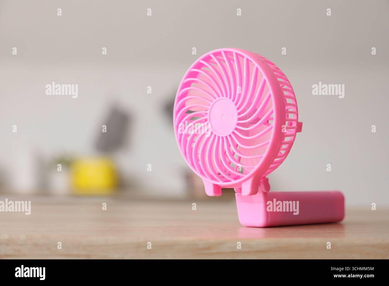 Pink mini fan on table in kitchen, closeup Stock Photo