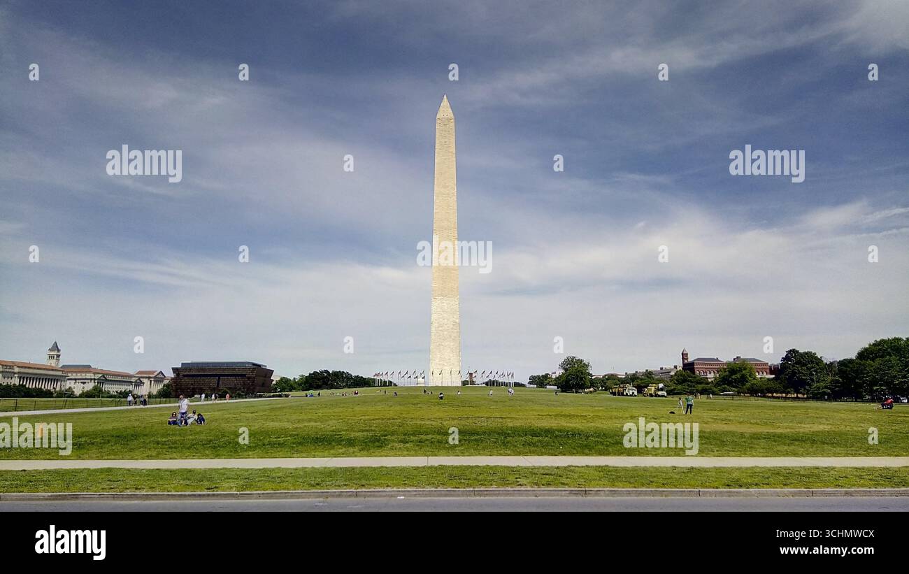 The Washington Monument towering over the National Mall, Washington D.C., with visitors enjoying the vast green lawn. Stock Photo