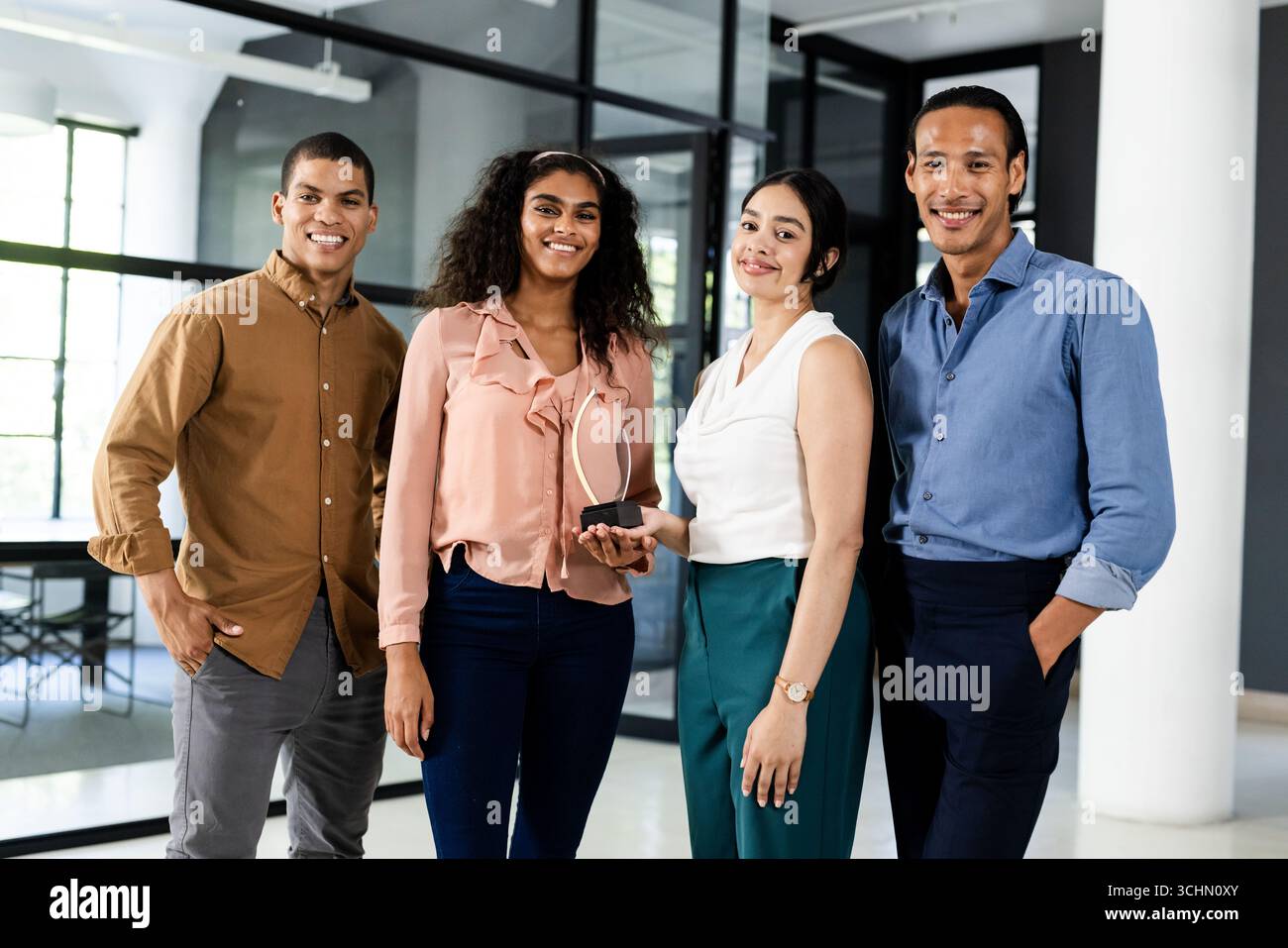 Diverse business team smiling confidently while holding award in modern office Stock Photo