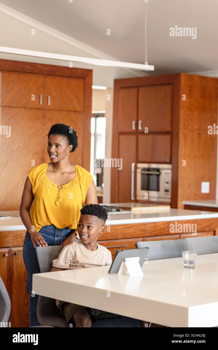 Mother and son smiling while using tablet at home in modern kitchen Stock Photo