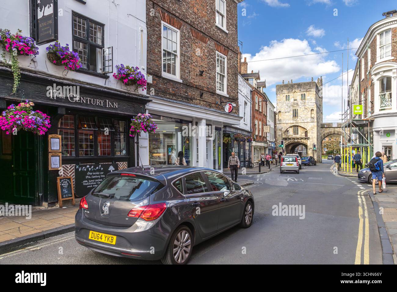 Monk Bar in York, North Yorkshire, England. A medieval gatehouse with flower baskets, pedestrians, and historic architecture on a sunny day. Stock Photo