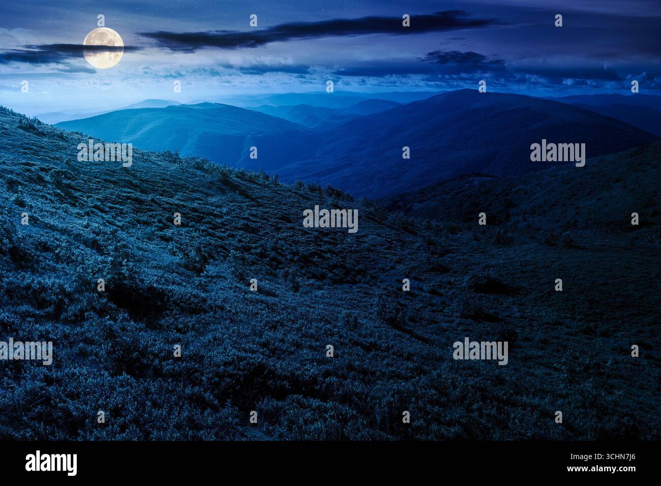 mountain landscape in summer at night. beautiful view of rolling green hills and alpine meadows in full moon light. scenery with clouds on the dark sk Stock Photo
