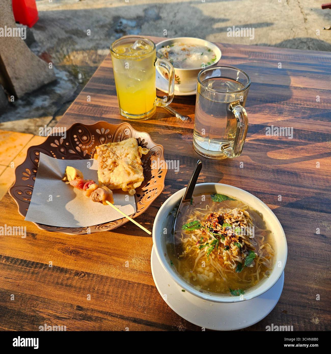 Traditional Indonesian breakfast with chicken soup, toast, and drinks served on wooden table - Smartphone Captured Stock Image