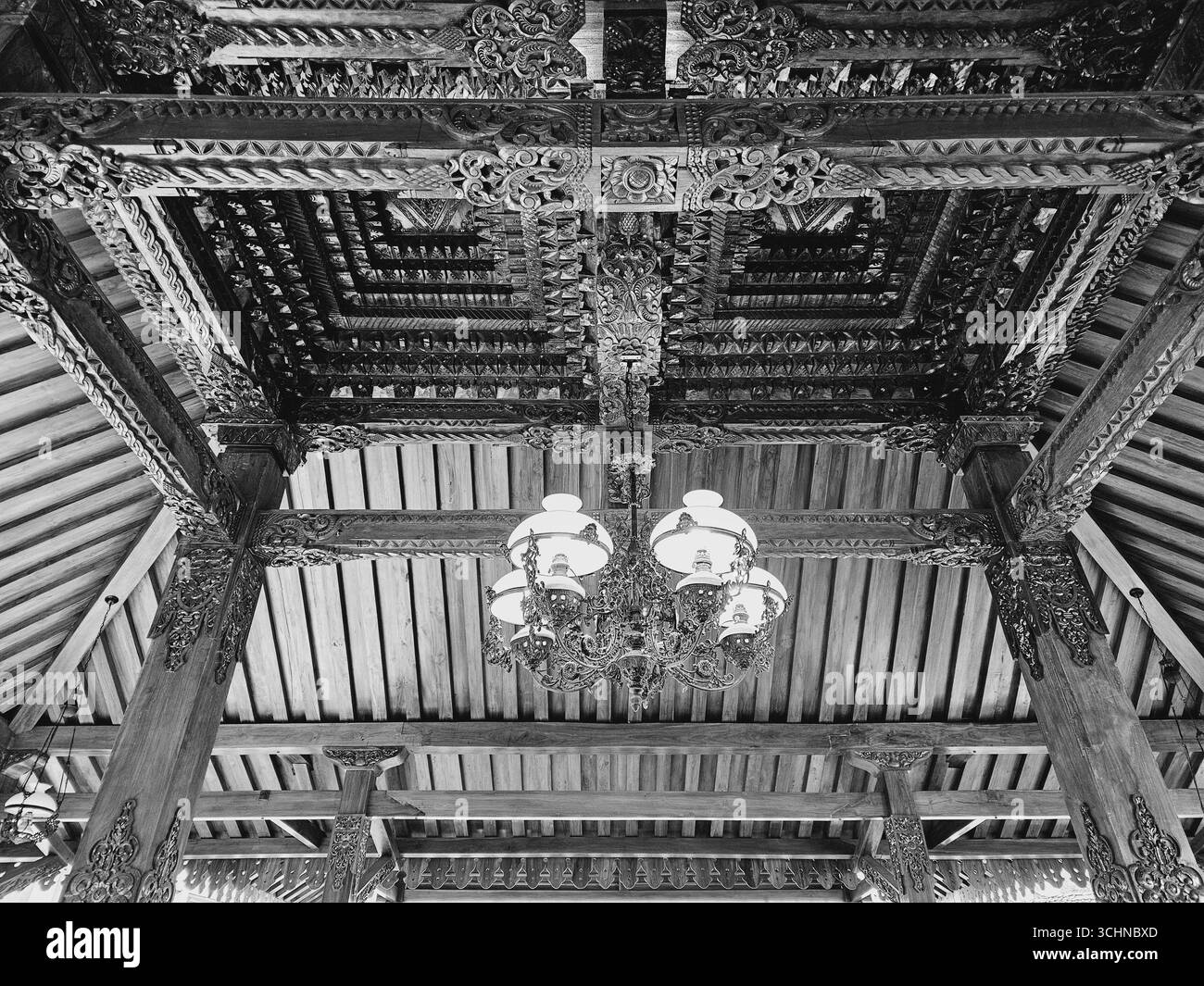 Black and white interior view of traditional Javanese joglo wooden ceiling with chandelier - Smartphone Captured Stock Image