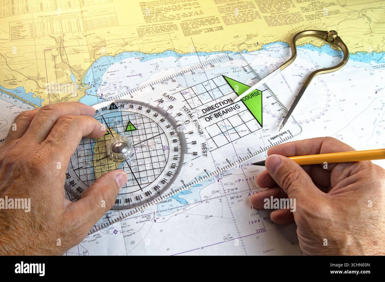 Man, Sailor, Navigator Plotting A Course On A Paper Navigation Chart Using Straight Brass Dividers And A Plastic Perspex Portland Plotter, UK Stock Photo
