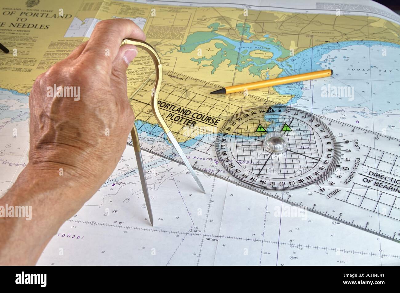 Man, Sailor, Navigator Plotting A Course On A Paper Navigation Chart Using Straight Brass Dividers And A Portland Course Plotter, UK Stock Photo