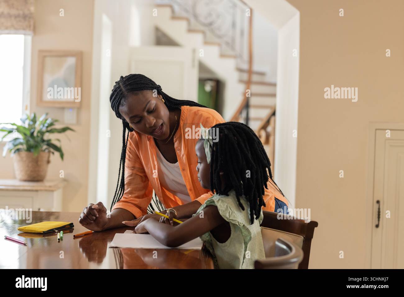 Mother helping daughter with homework at home, fostering learning and support Stock Photo