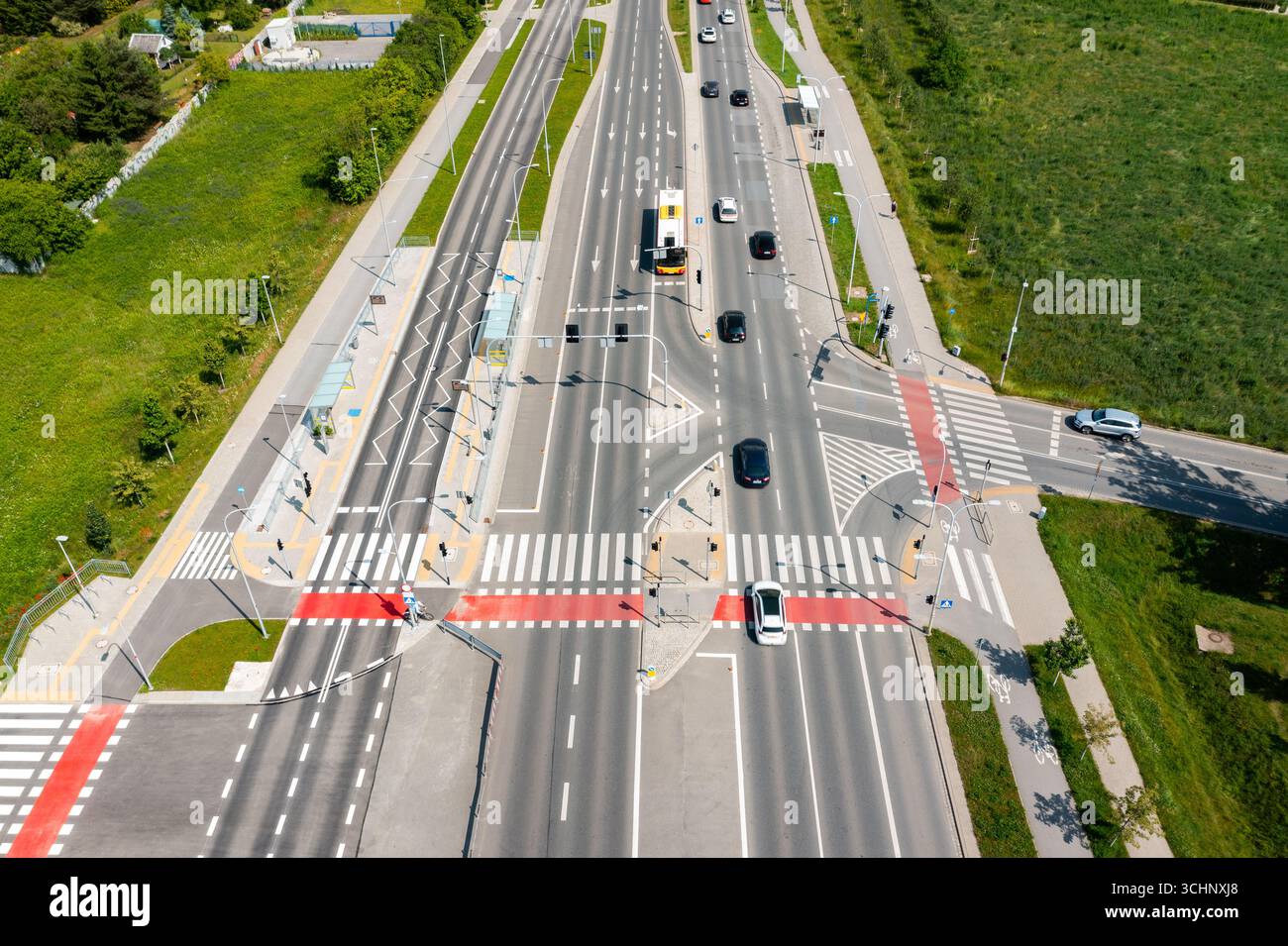 Major multilane road intersection with public bus stop and crosswalks in suburban area with cars in motion Stock Photo