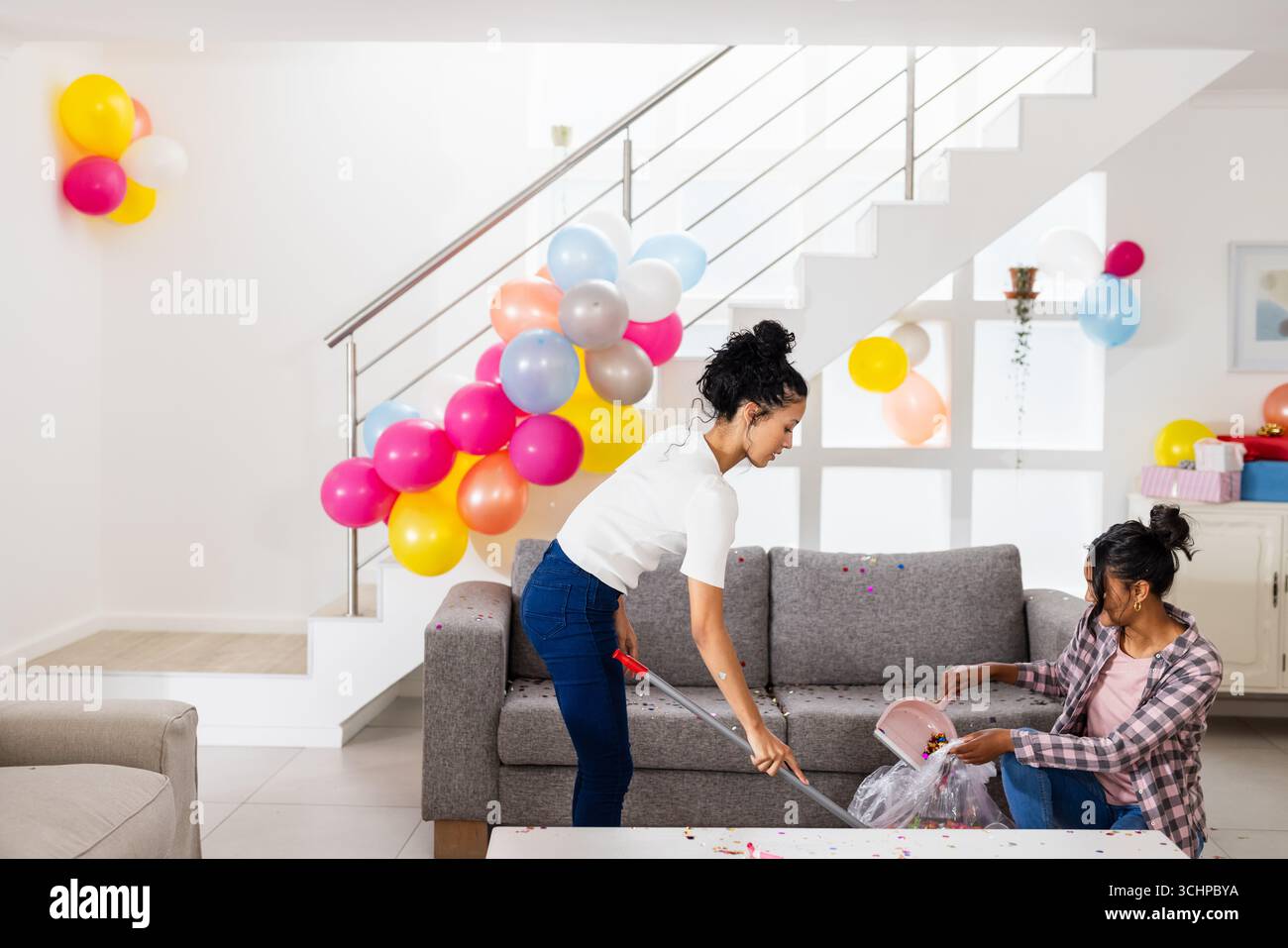 Celebrating at home, two diverse female friends cleaning up after party ...