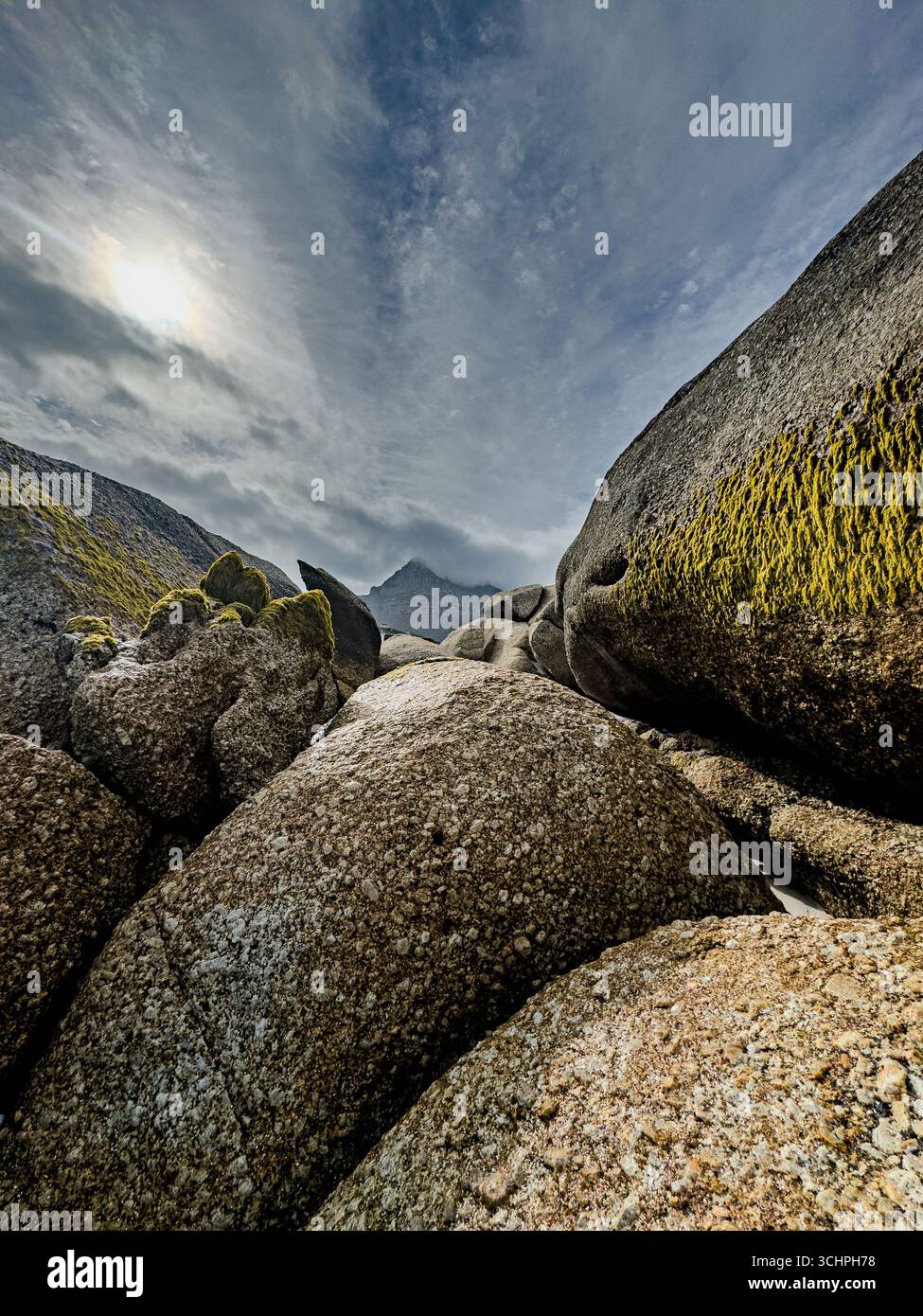 A low-angle, wide-angle shot of a rocky beach in Cape Town. The photograph highlights the pristine, clear water flowing over the sand and rocks in the - Smartphone Captured Stock Image
