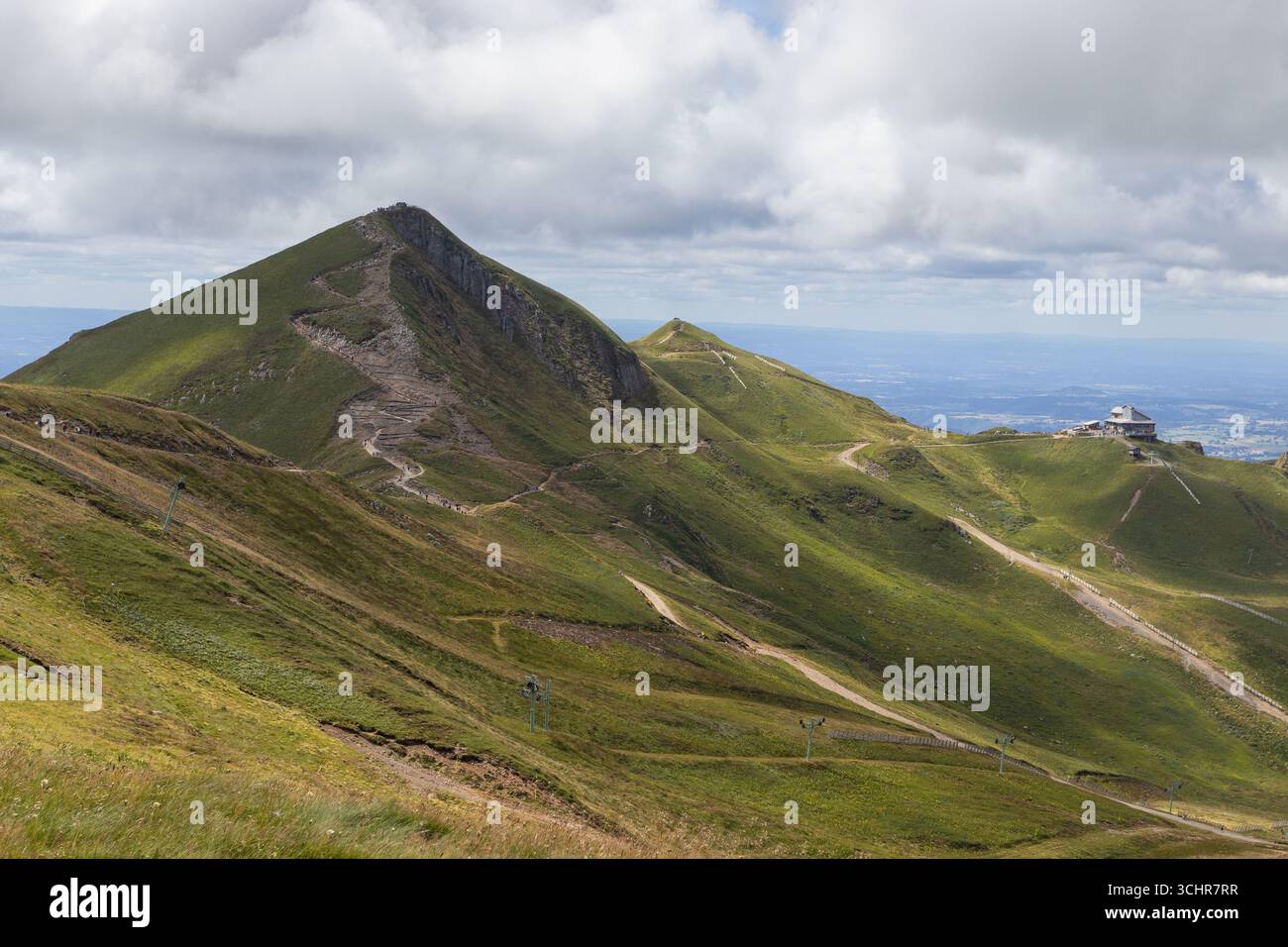 Summer view of the summit of Puy de Sancy (left) and the chain of puys leading to the end station of the Cable car of Sancy on the right. Puy de Sancy - Stock Image