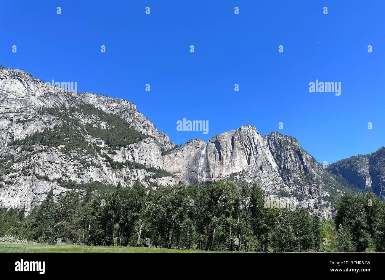 Yosemite Falls cascading down the granite cliffs with green trees and meadow in the foreground, Yosemite National Park, California, - Smartphone Captured Stock Image