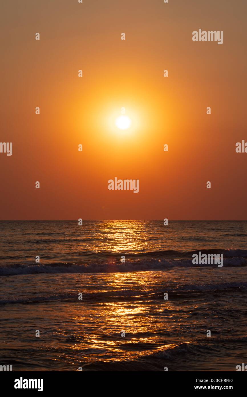 Serene sunset illuminating ocean waves with vivid warm tones and reflecting golden light. An atmospheric image capturing tranquility, natural beauty, Stock Photo