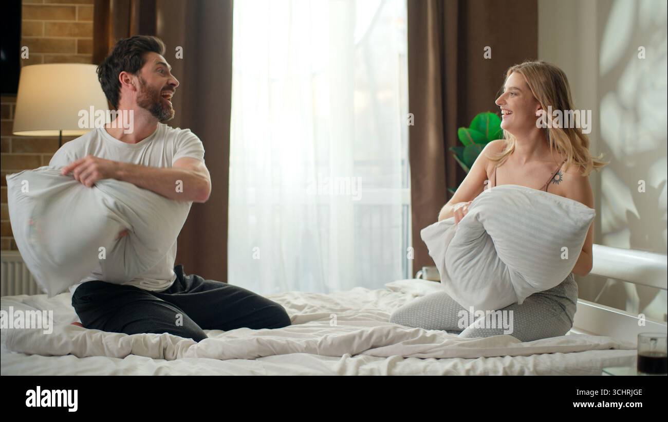 joyful-family-positive-caucasian-married-couple-playing-pillows