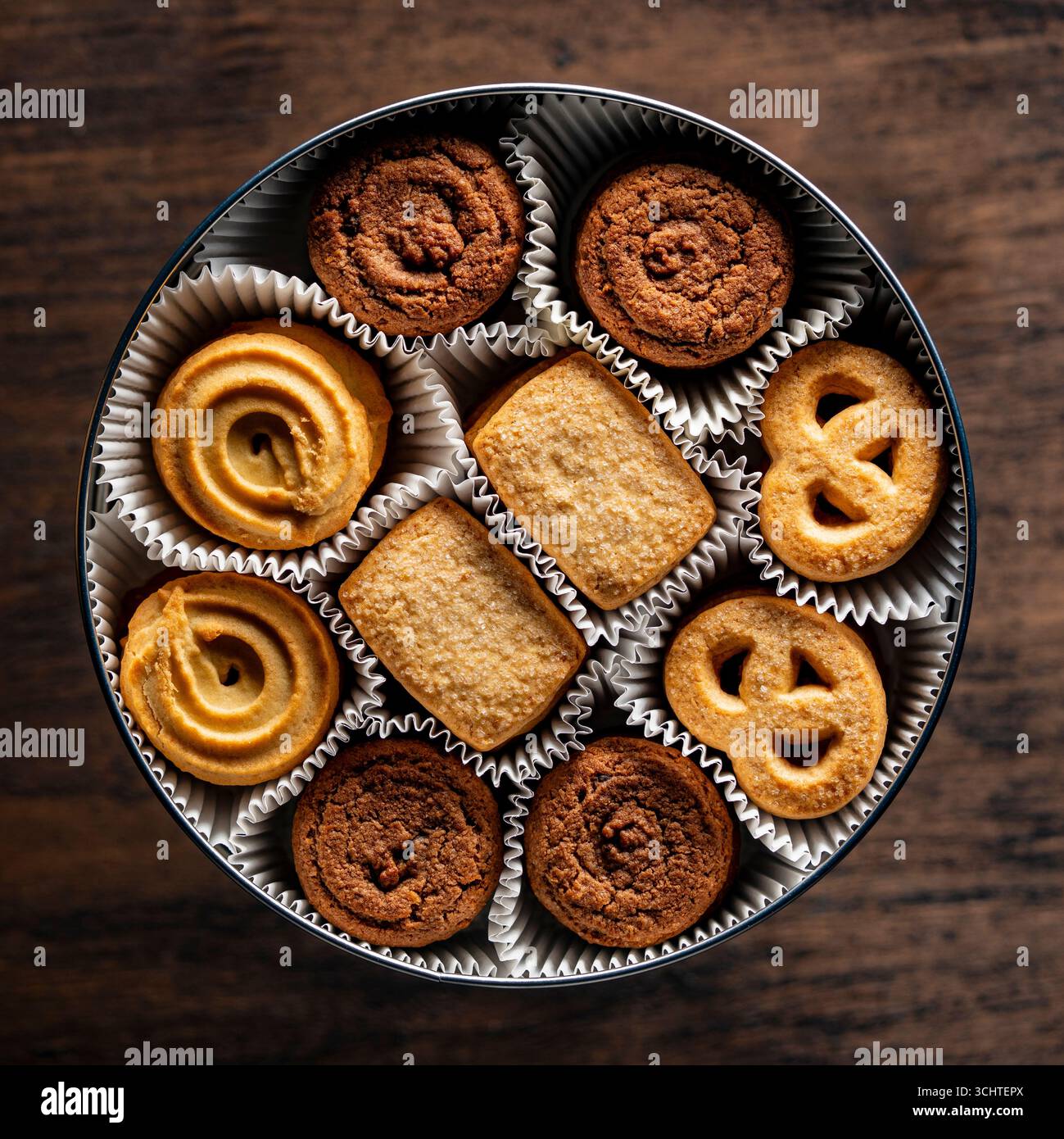 Crispy crumbly shortbread cookies in a round metal box on wooden table, top view, close up Stock Photo