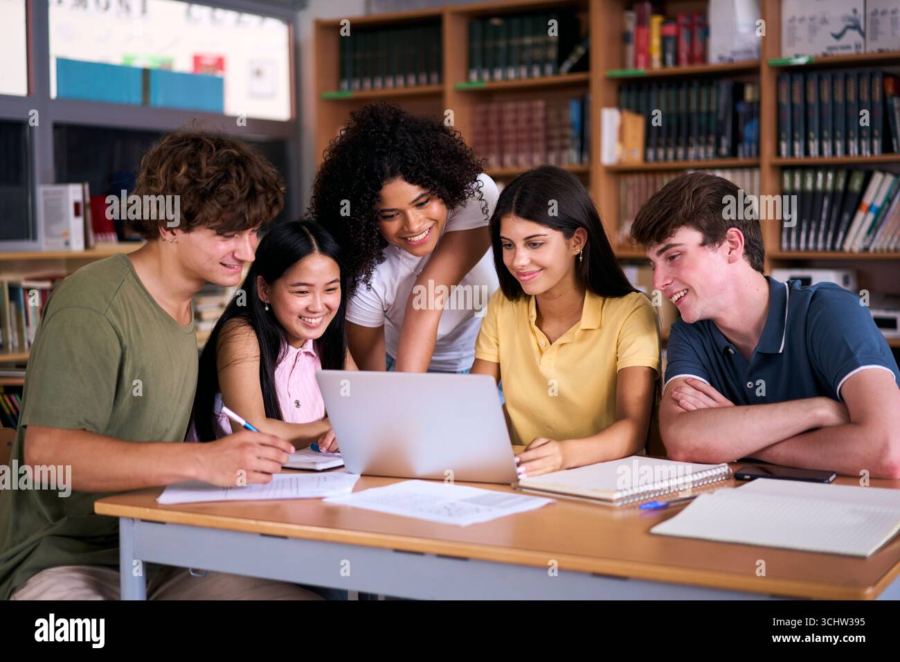 High school students collaborating on project in library using laptop Stock Photo