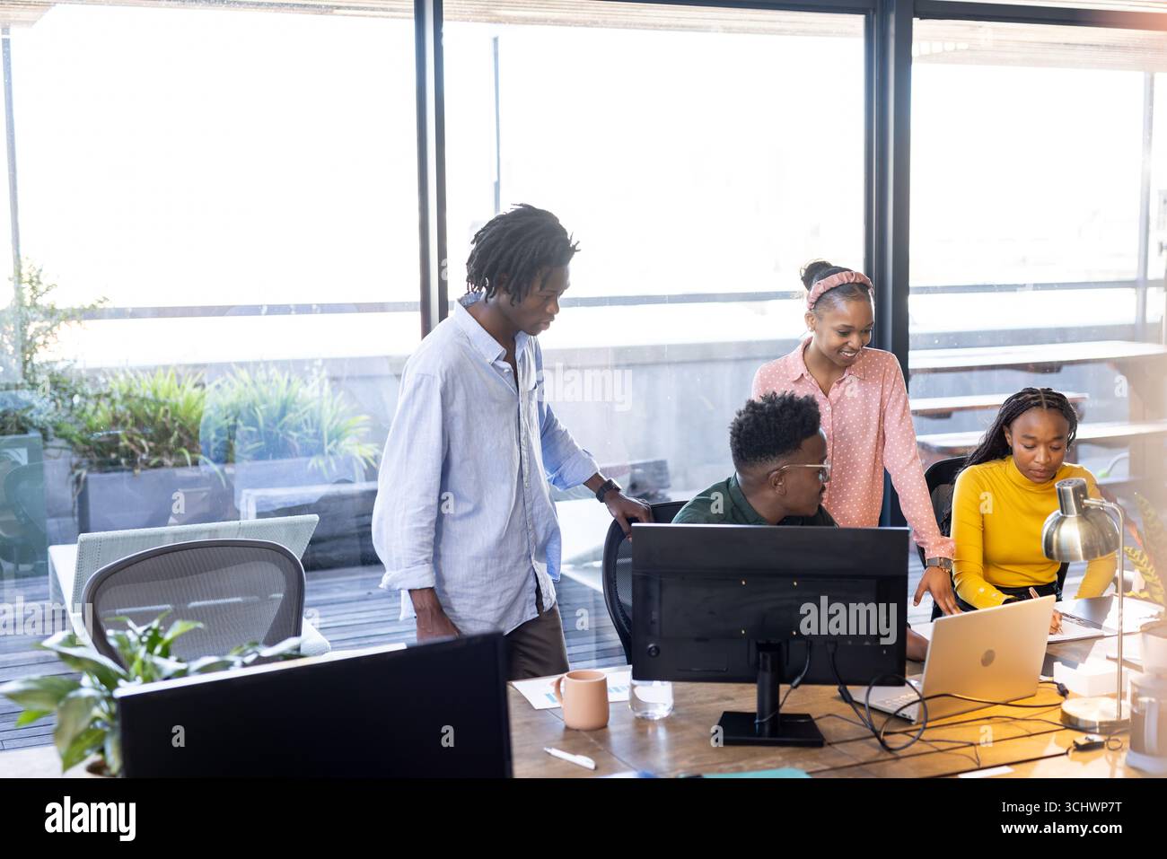 Team collaborating on project at office, using laptops and discussing ideas Stock Photo