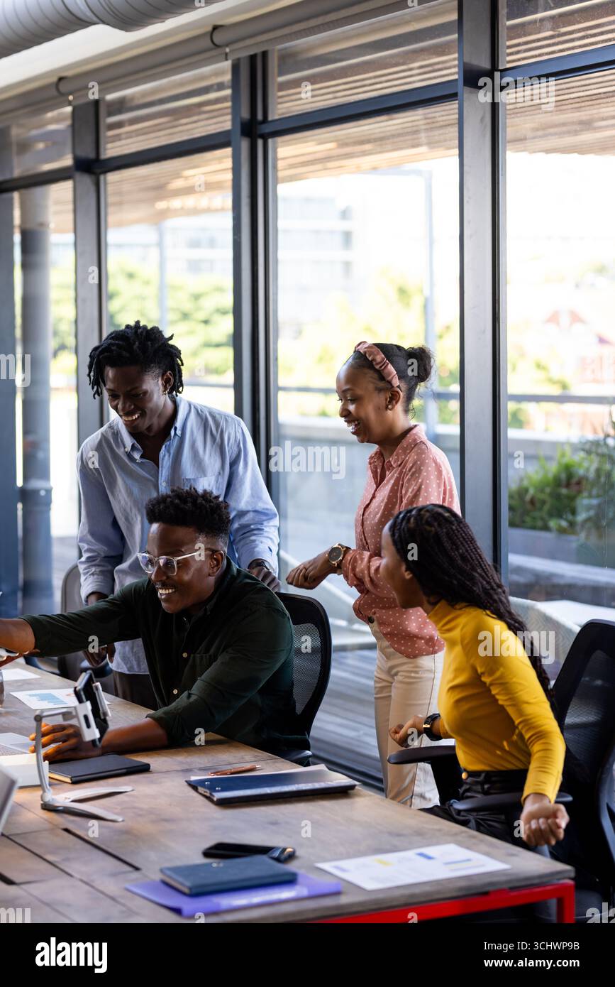 In office, team collaborating using digital devices, sharing ideas enthusiastically Stock Photo