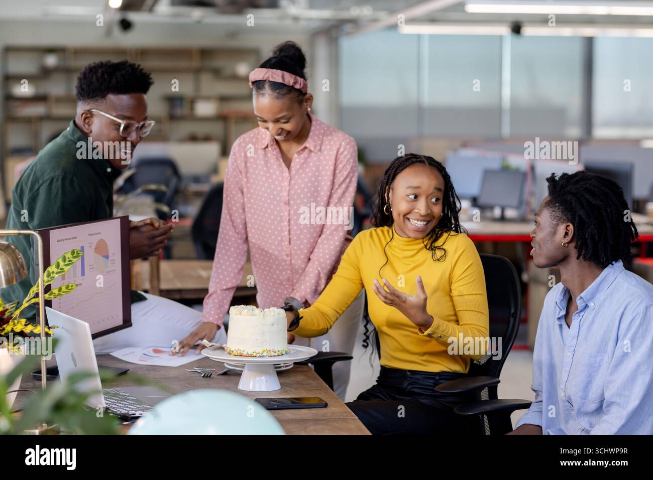 Team collaborating in modern office, discussing project while enjoying cake together Stock Photo