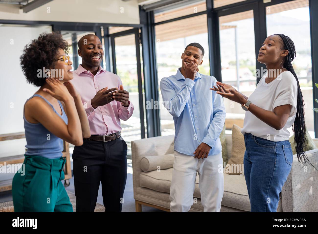 Colleagues laughing and chatting in modern office during casual team meeting Stock Photo