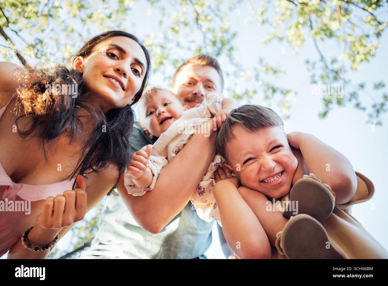 Group of four family members, including two children, smiling and ...