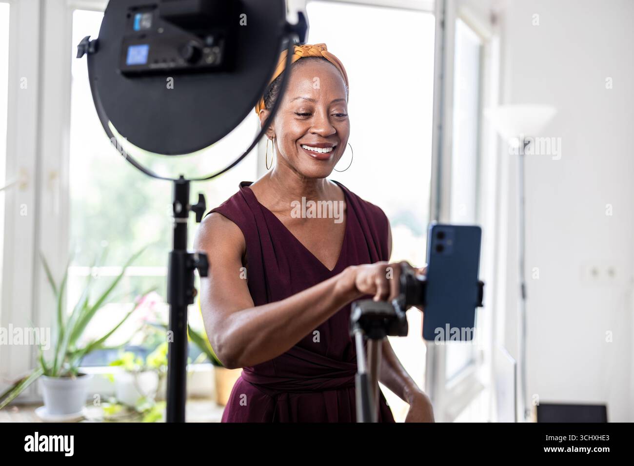 Smiling beautiful woman vlogging using her mobile phone at home Stock Photo