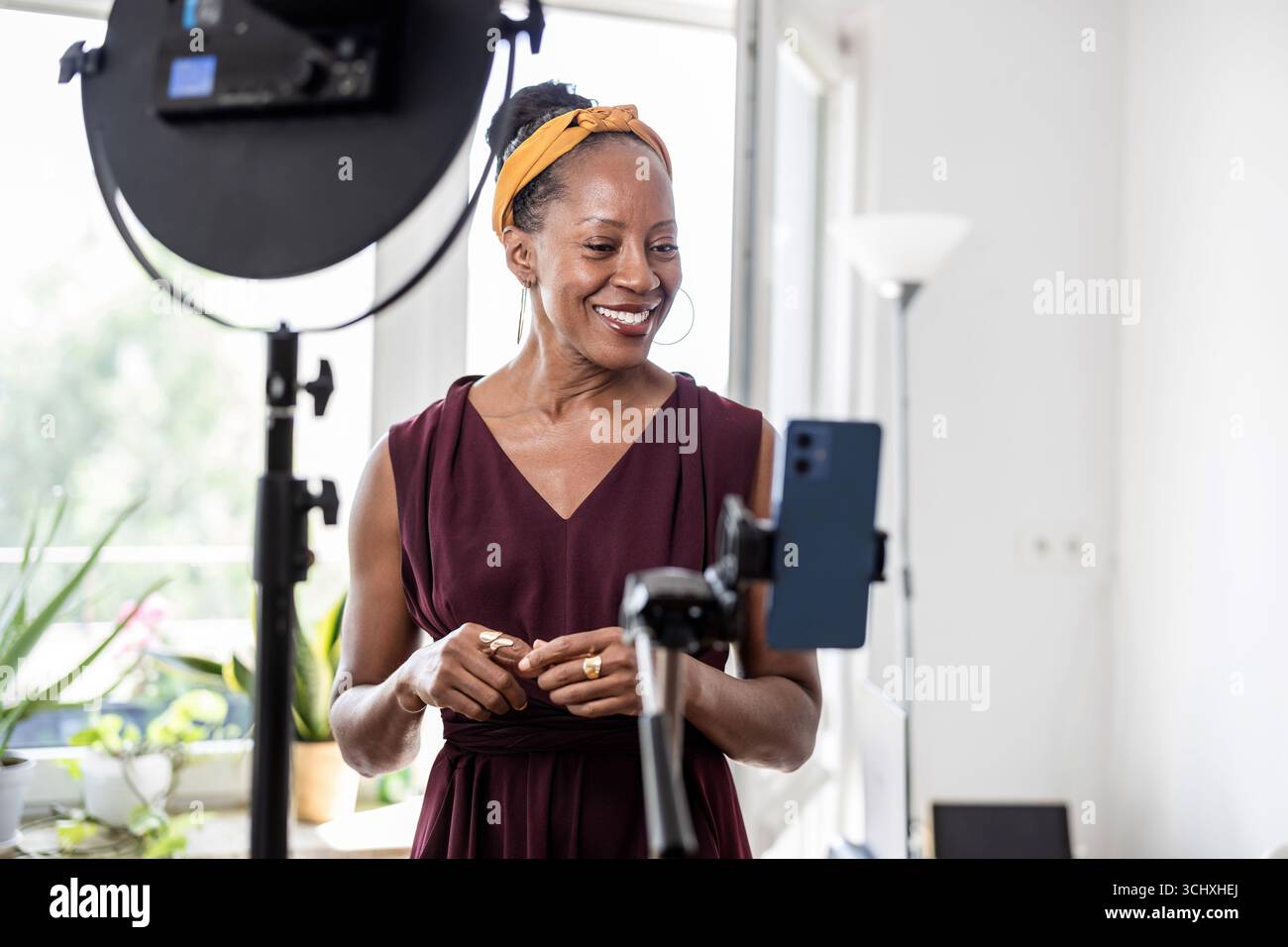 Smiling beautiful woman vlogging using her mobile phone at home Stock Photo