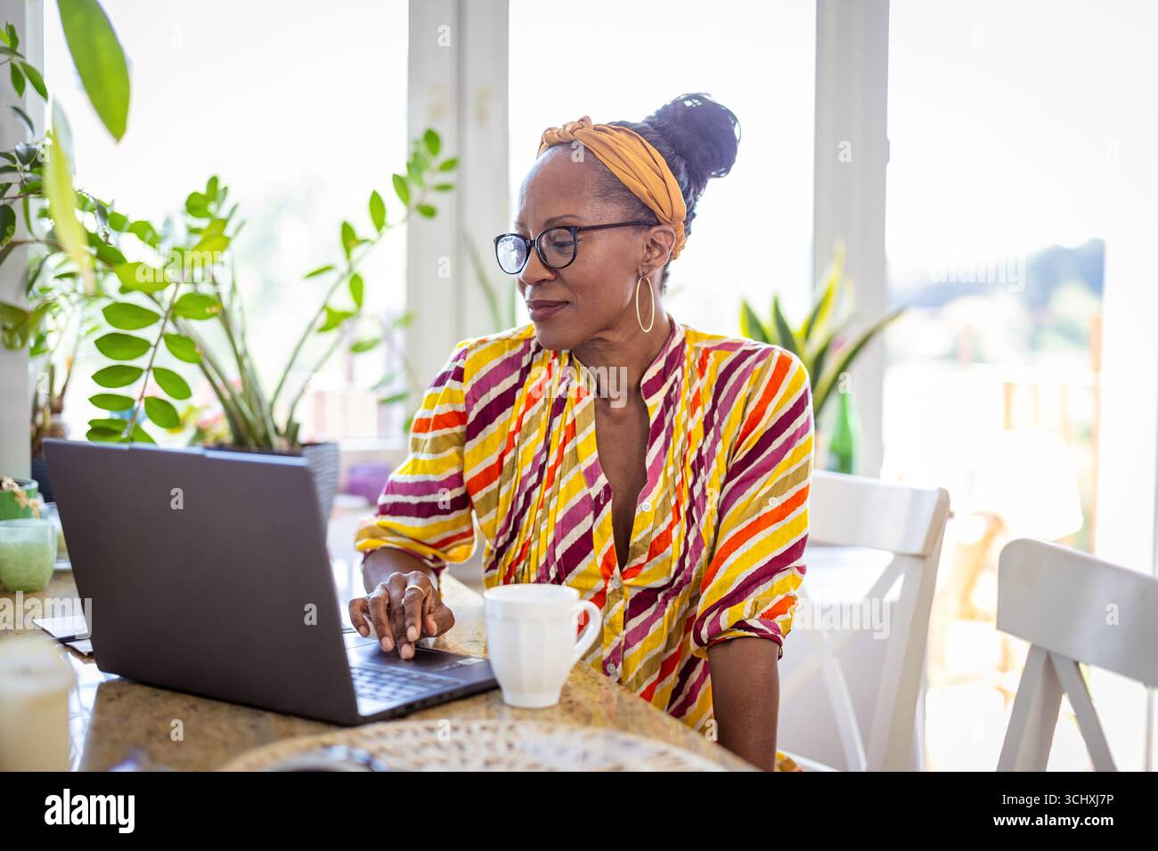 Happy woman drinking coffee and using laptop at home Stock Photo