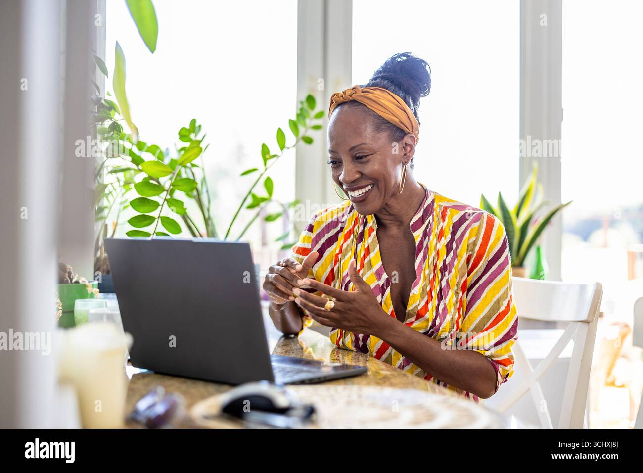 Smiling woman using laptop while sitting at desk in office Stock Photo