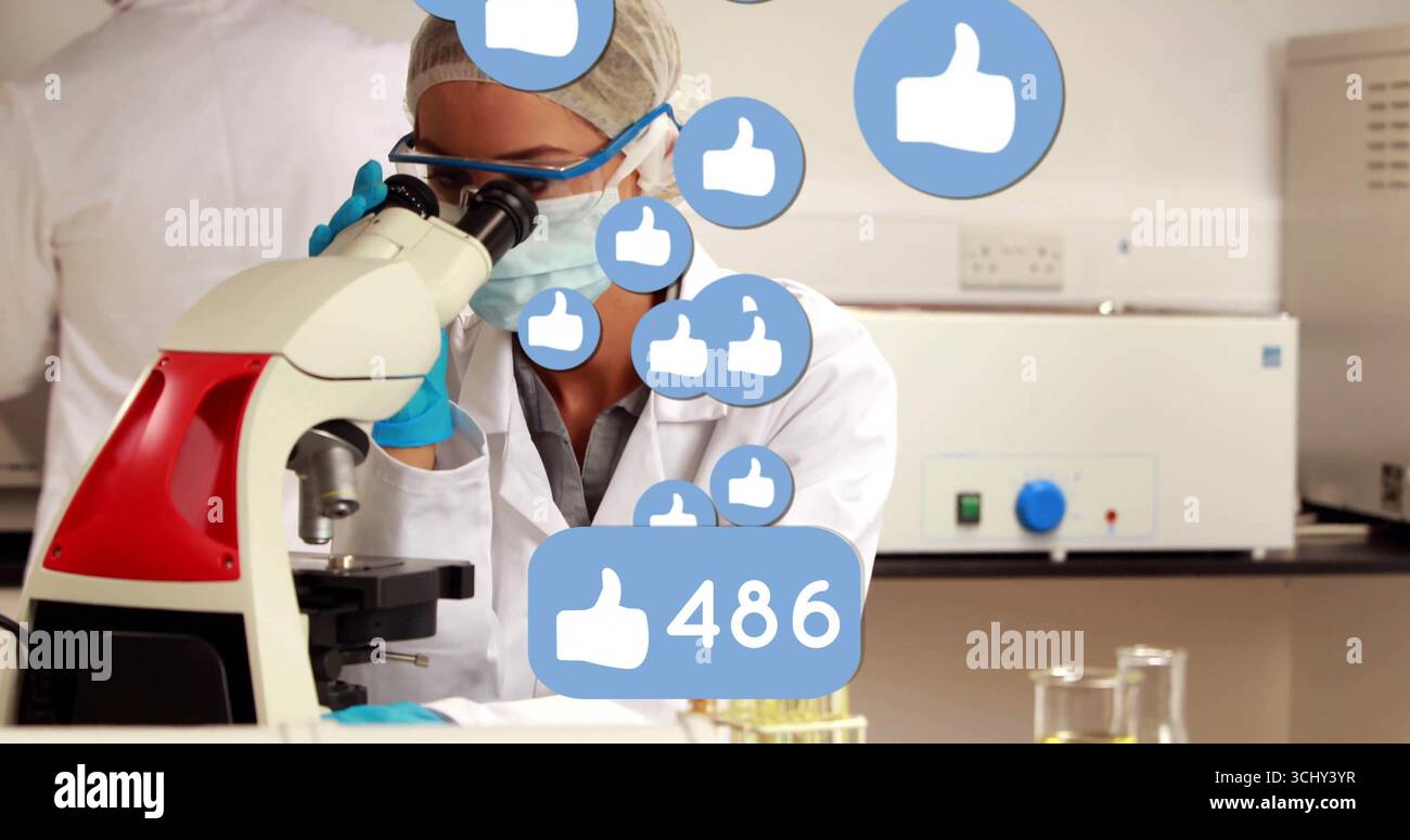 Observing scientist wearing coat examining microscope in lab, liquid test tubes and thumbs-up icons Stock Photo
