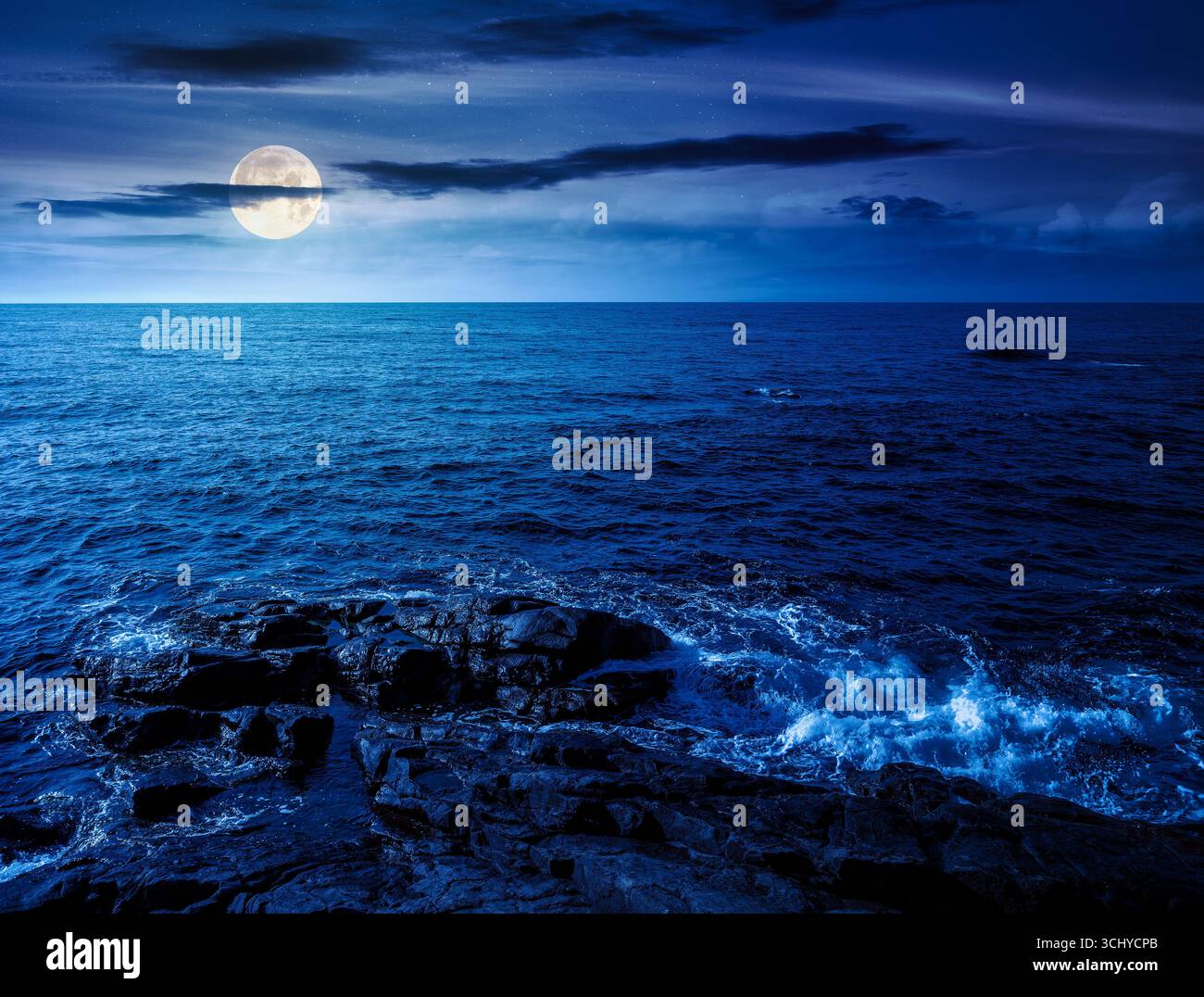 sea coast with rocks and boulders at night. calm summer vacation background at the seashore. wonderful scene for relax and leisure at the seaside in f Stock Photo