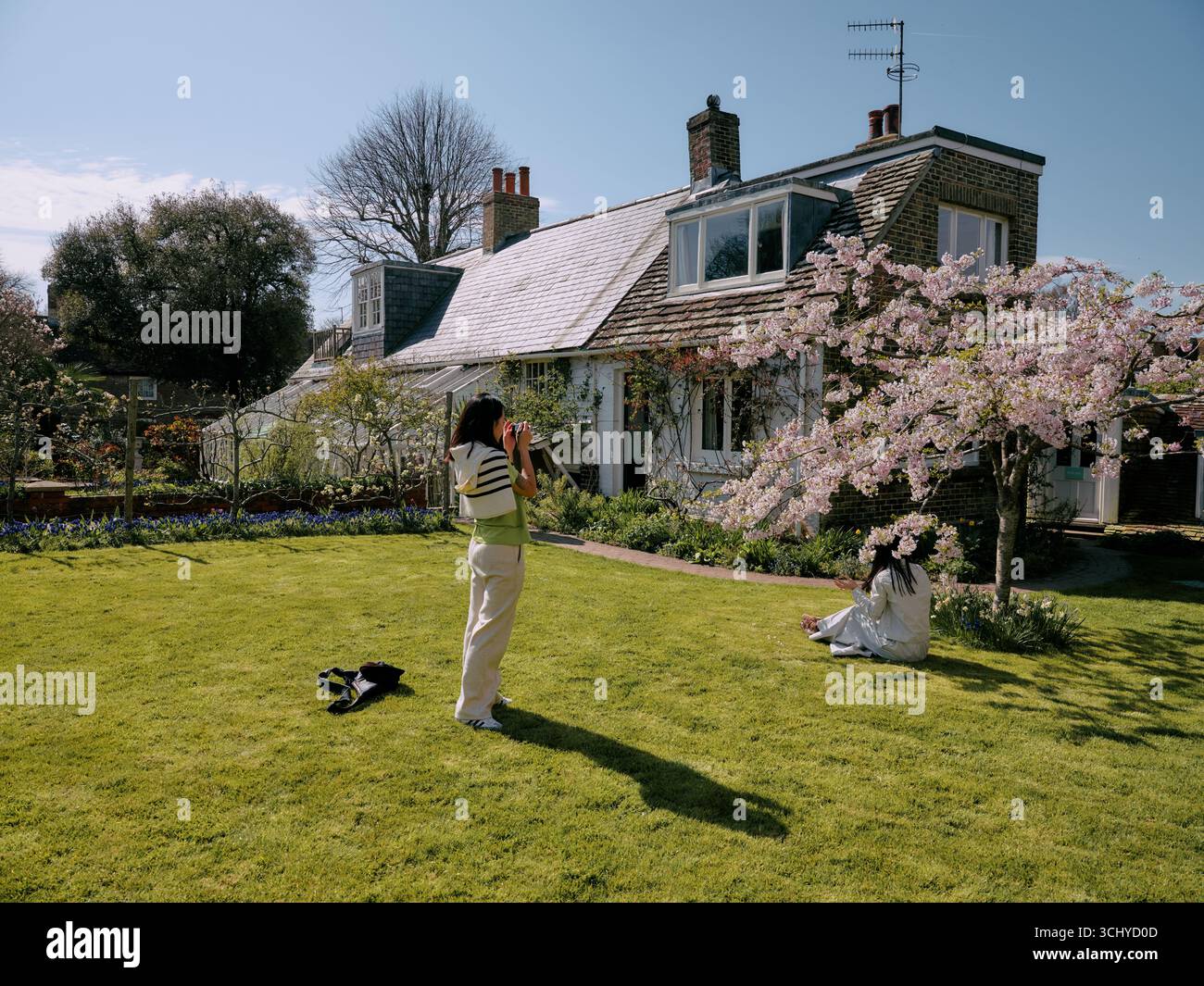 Tourists enjoying the blossom at Monk's House and garden in Rodmell near Lewes where novelist Virginia Woolf lived. East Sussex England UK Stock Photo