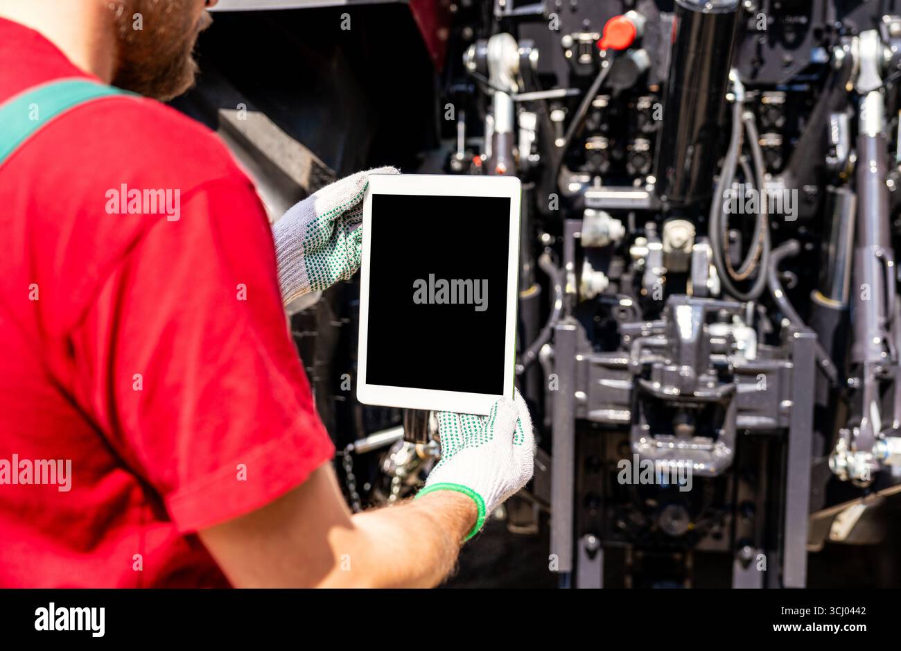 Agricultural mechanic using digital tablet for wireless machinery diagnostics. Stock Photo
