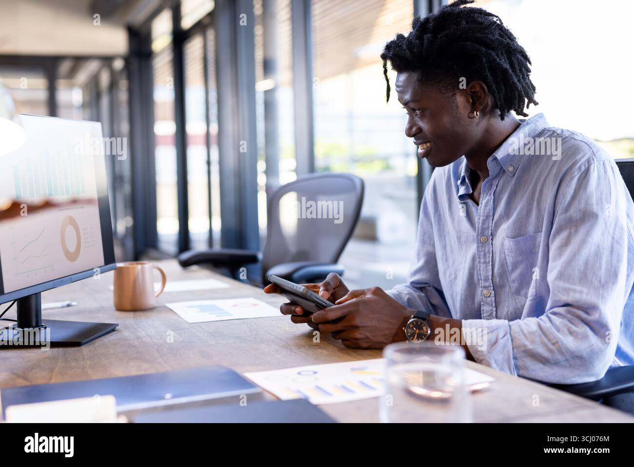 African American man using tablet and computer at office, analyzing data charts Stock Photo