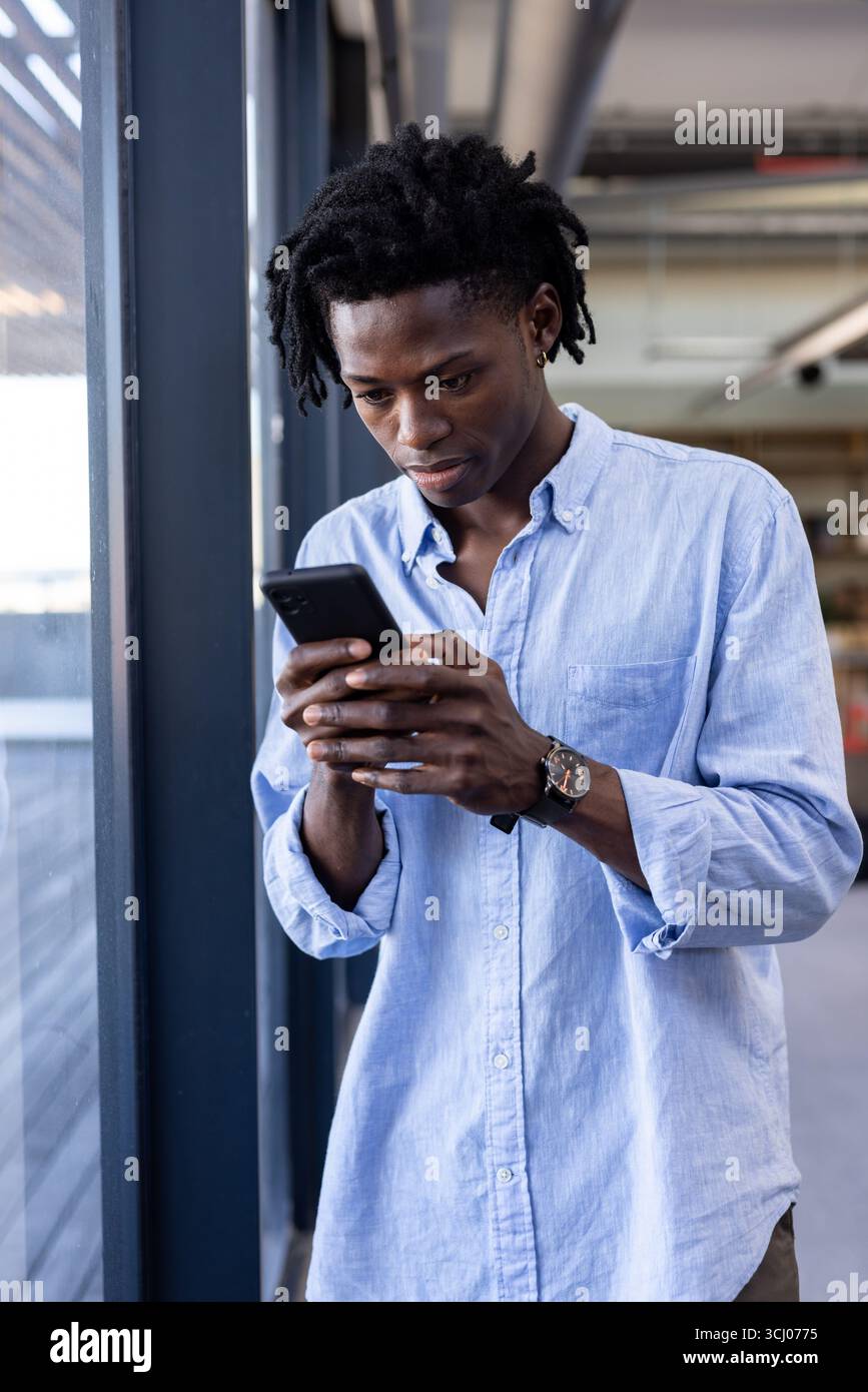 Young man in office using smartphone, concentrating on work tasks Stock Photo