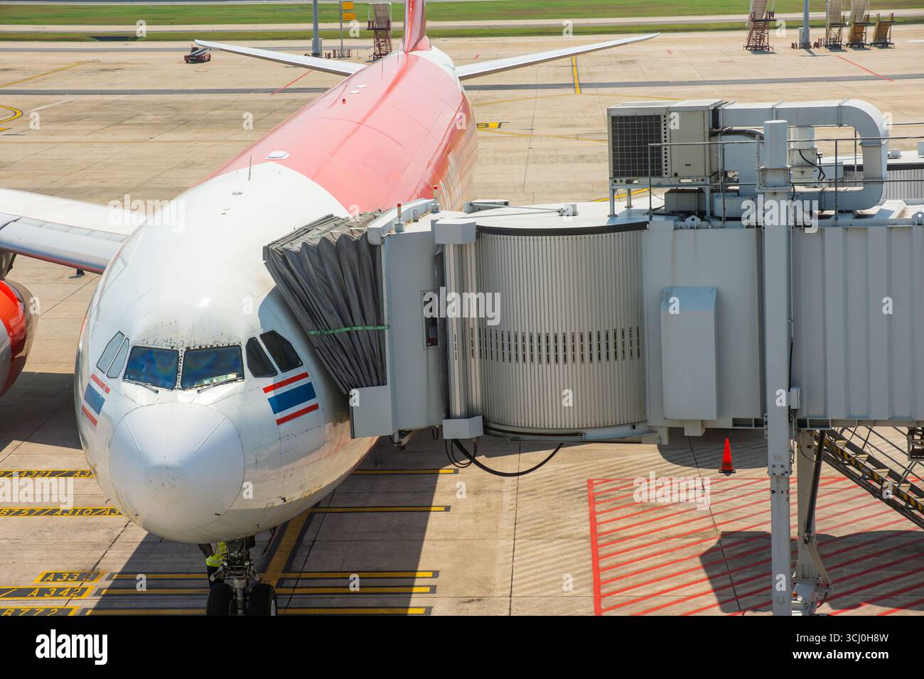 Airplane connected to passenger boarding jet bridge at Don Mueang International airport on in Bangkok city preparing for boarding or disembarkation at Stock Photo
