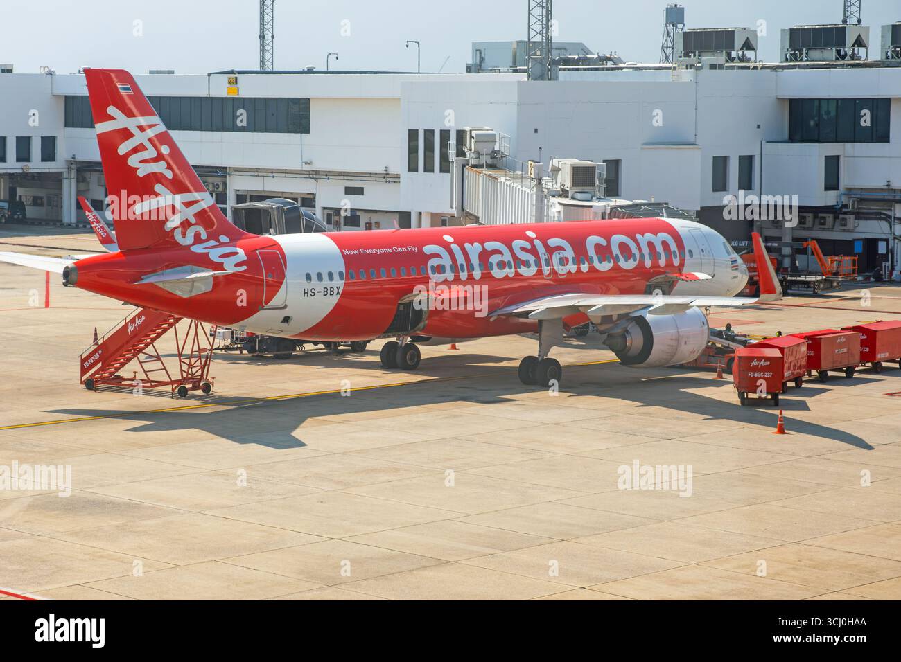 Bangkok, Thailand - March 10, 2025 : AirAsia aircraft parked at gate at Don Mueang International Airport with ground service equipment and terminal Stock Photo