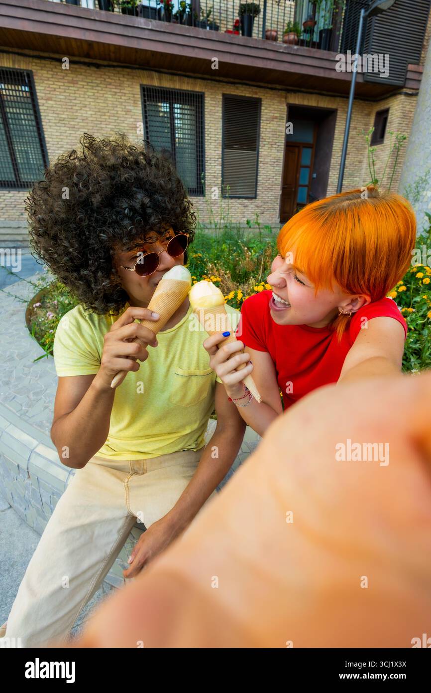 Happy couple taking a selfie while eating ice cream outdoors Stock Photo