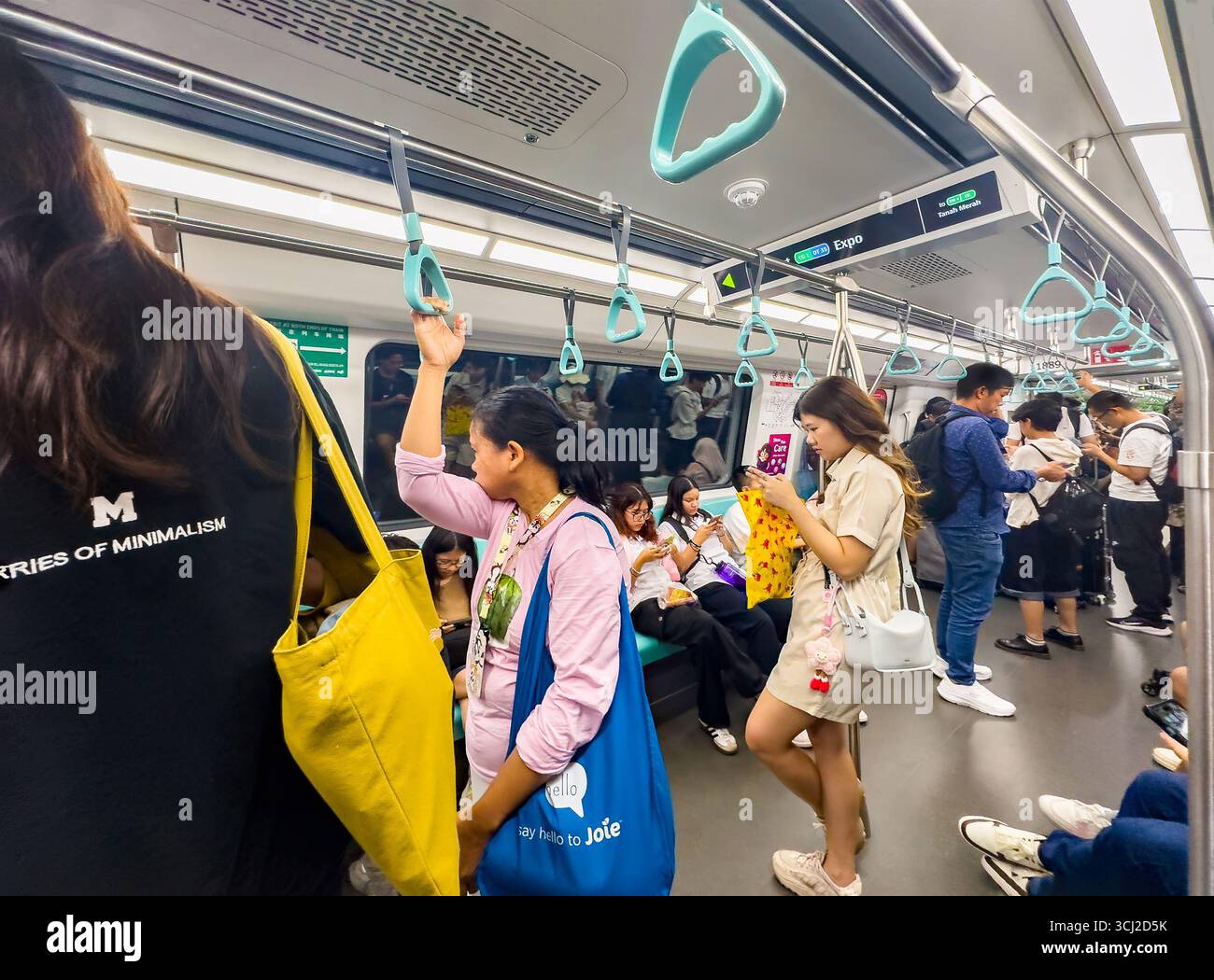A crowded subway train with standing passengers holding onto handrails during a busy commute in an urban environment singapore MRT asia - Smartphone Captured Stock Image