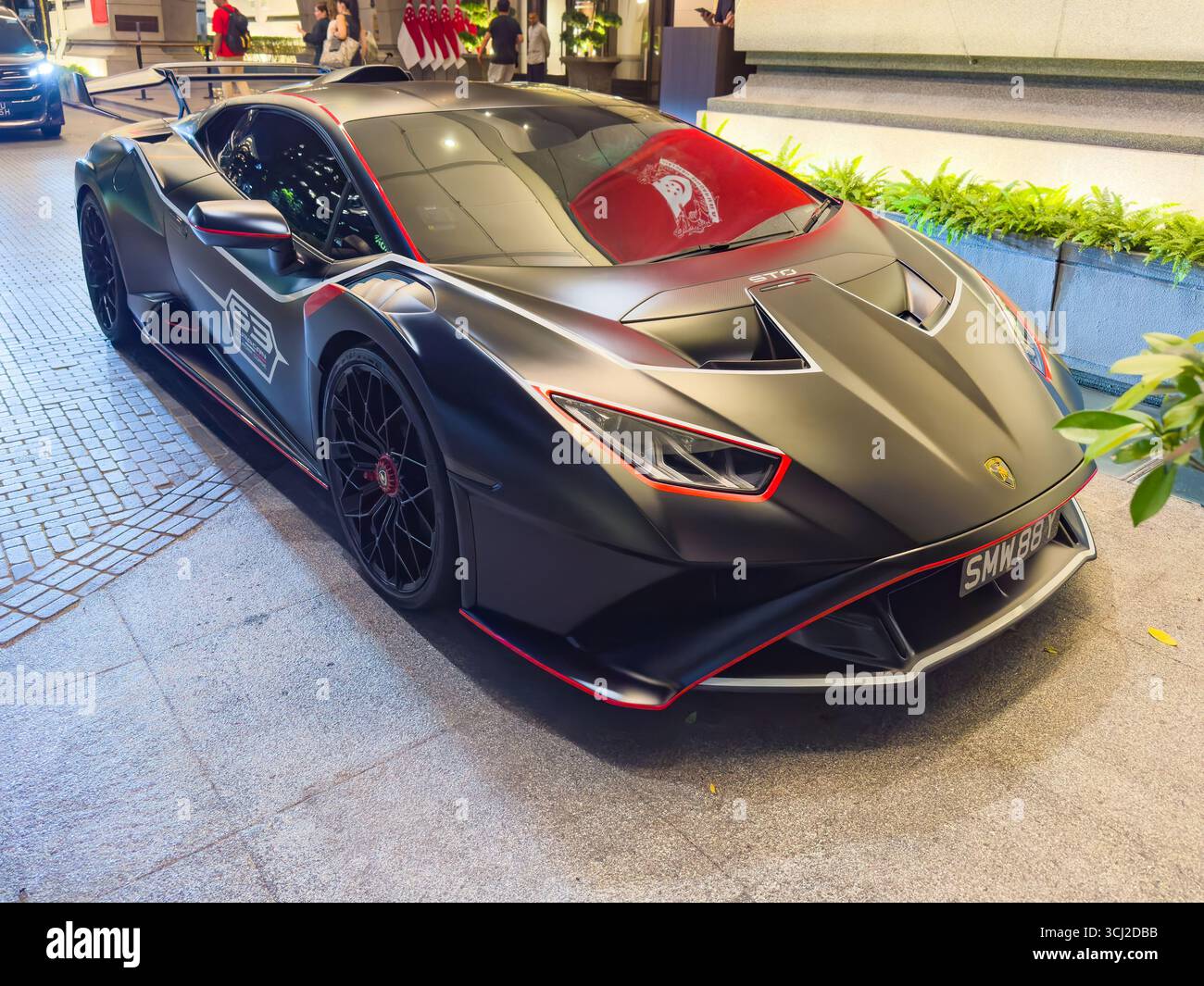 Sleek black Lamborghini Huracan sports car with red details parked on a singapore city street under bright lights - Smartphone Captured Stock Image