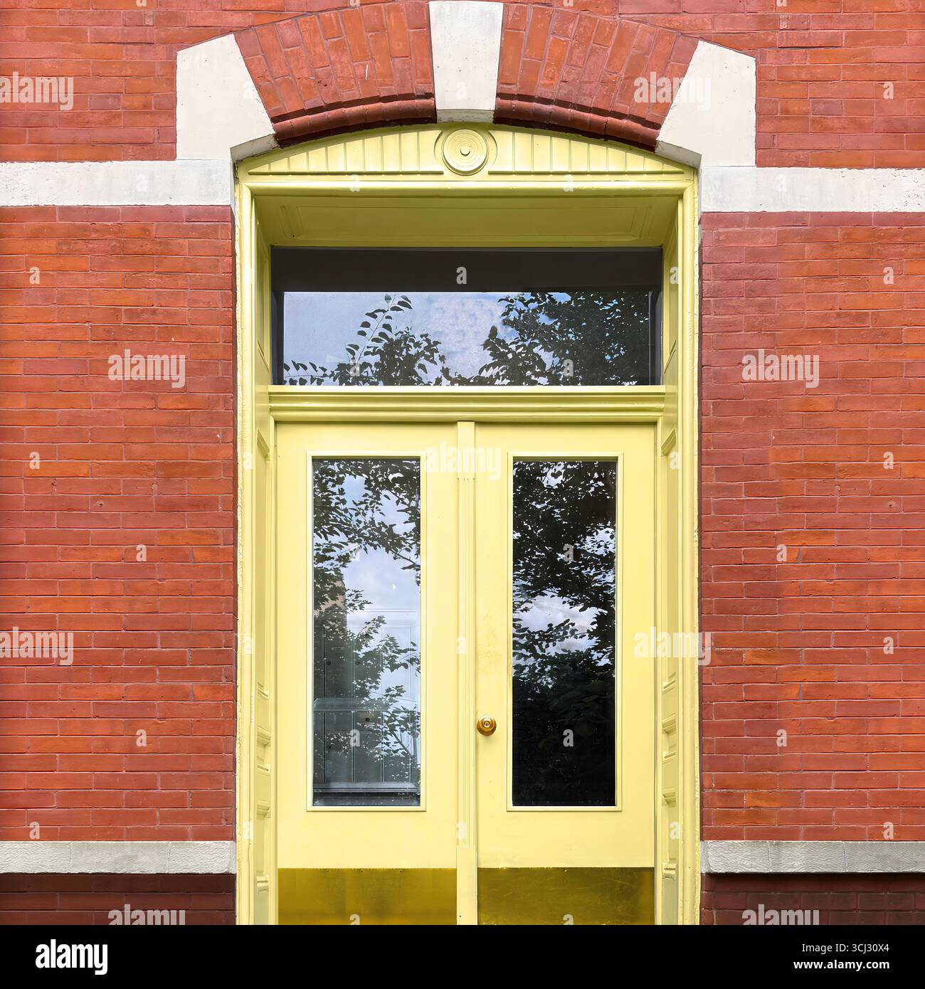 Pale yellow double door with glass panels framed by arched red brick facade in Chicago. - Smartphone Captured Stock Image